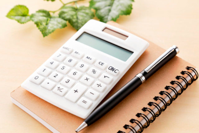 机に置かれた手帳とペンと電卓