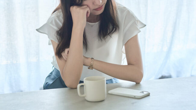 椅子に座って肘をついて考える女性