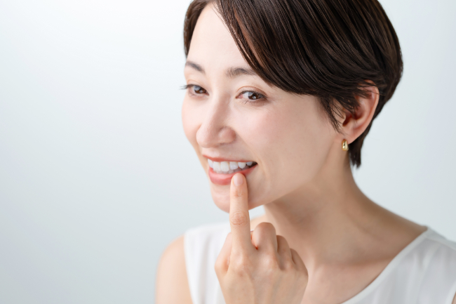 インプラントにした歯を指さして笑顔を見せる女性