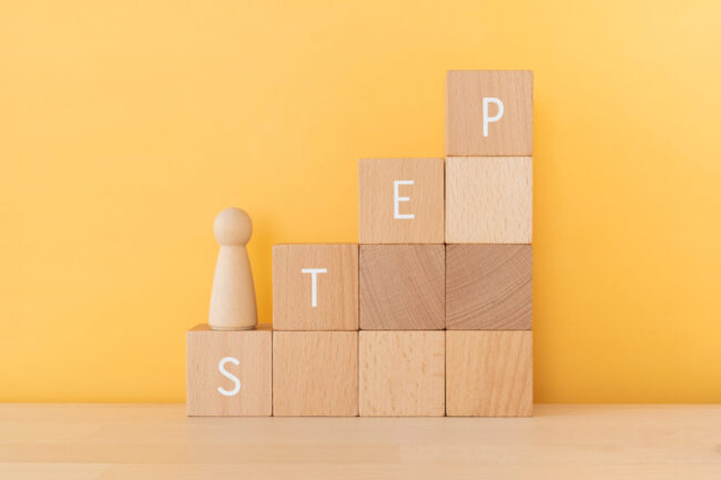 STEPと書かれた積み木をのぼる木の人形