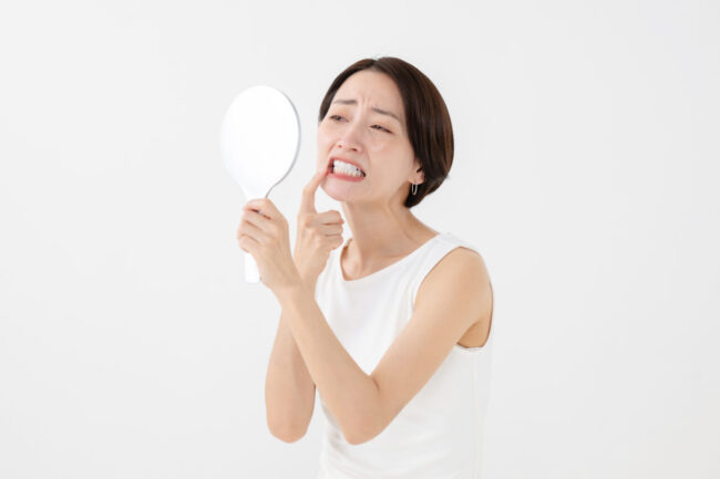 歯を失うことで、自分に自信が持てなくなるのではないかと危惧して鏡を見ている女性